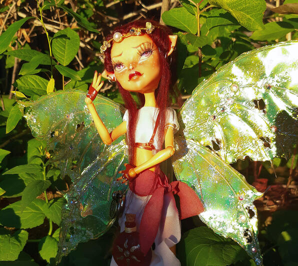 Orange-skinned redheaded fairy with large yellow moth wings, a white shirt and pants, and a red sash.